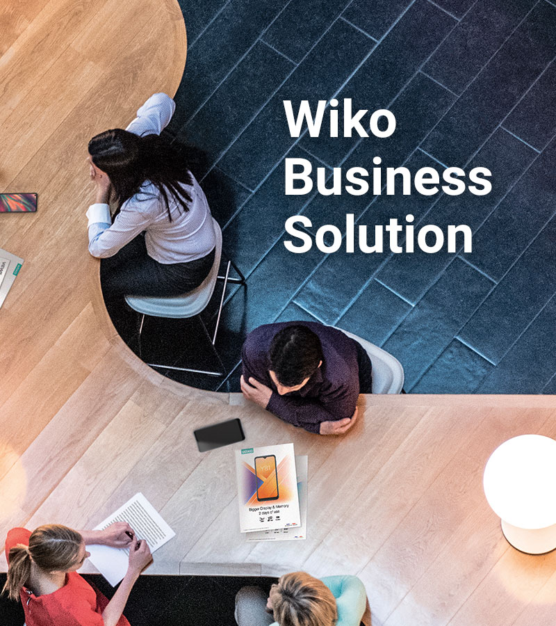 Vue de haut de personnes assises autour d'un bureau en bois représentant le W de Wiko - titre intégré : Wiko Business Solutions